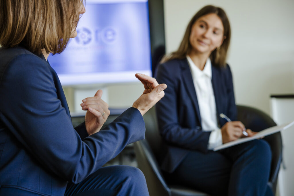 Auf dem Bild sind zwei Führungskräfte im Gespräch während eines Trainings zur Führungskräfteentwicklung zu sehen. Sie tauschen sich über Leadership, Mitarbeiterführung und die Gestaltung einer positiven Unternehmenskultur aus. Das Bild veranschaulicht praxisnahe Ansätze wie Coaching, Mentoring und Peer-Learning für nachhaltige Organisationsentwicklung.